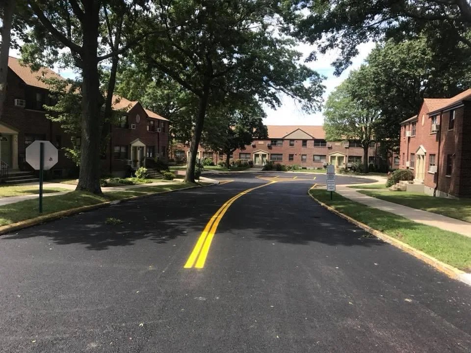 Completed commercial parking lot paving in Queens NY — smooth asphalt surface with drainage markings